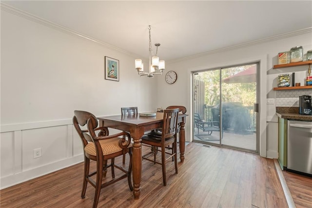 dining space with wood-type flooring, crown molding, and an inviting chandelier