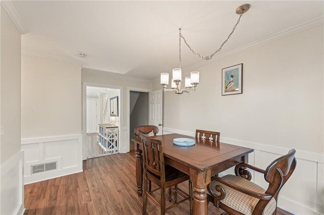 dining room with crown molding, hardwood / wood-style floors, and an inviting chandelier