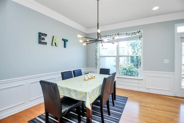 dining area featuring crown molding, a chandelier, and light hardwood / wood-style floors