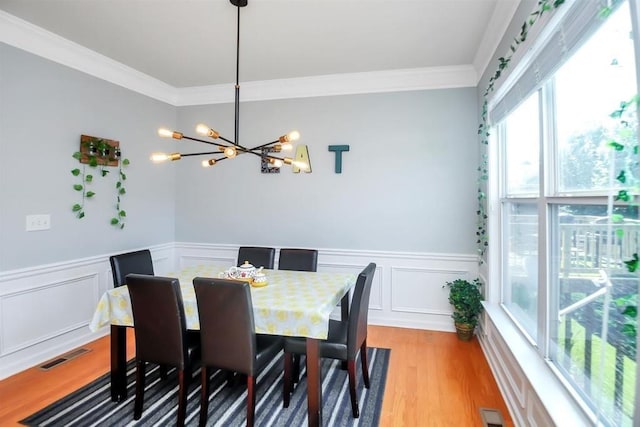 dining area with a chandelier, crown molding, and light hardwood / wood-style flooring