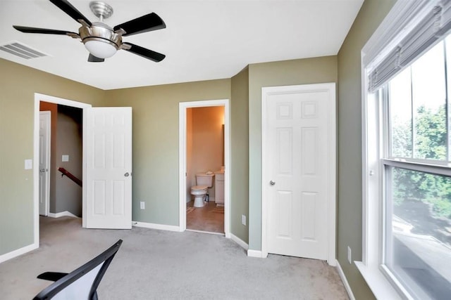 bedroom featuring light colored carpet, visible vents, a ceiling fan, ensuite bath, and baseboards