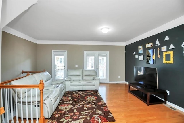 living room featuring ornamental molding, wood finished floors, visible vents, and baseboards