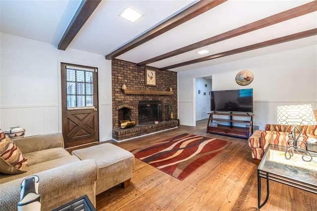 living area with beamed ceiling, wood finished floors, wainscoting, and a fireplace