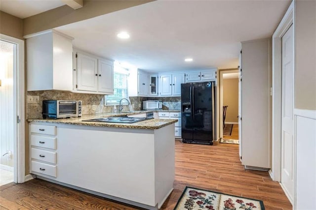 kitchen featuring black appliances, a peninsula, tasteful backsplash, light wood-type flooring, and white cabinetry