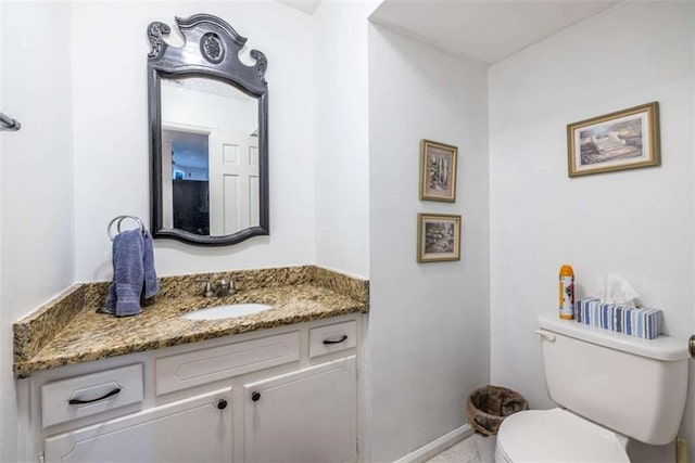 half bathroom featuring toilet, vanity, and baseboards