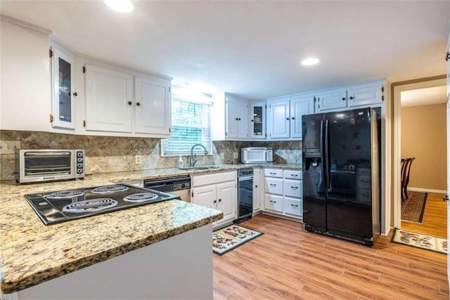 kitchen with black fridge, white microwave, a sink, stainless steel dishwasher, and light wood-type flooring