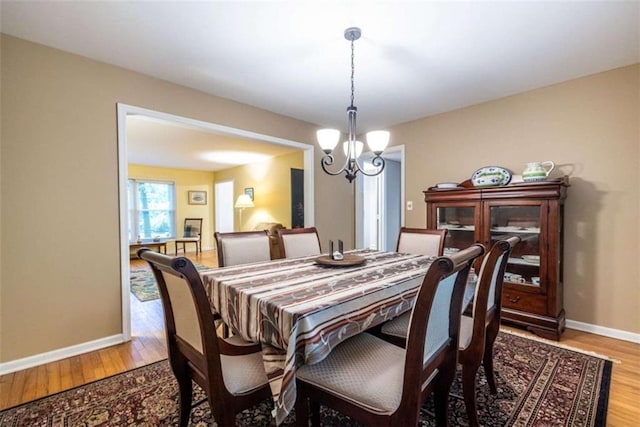 dining space with a chandelier, wood finished floors, and baseboards