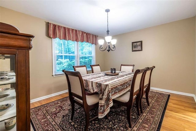 dining area with light wood-style floors, a chandelier, and baseboards