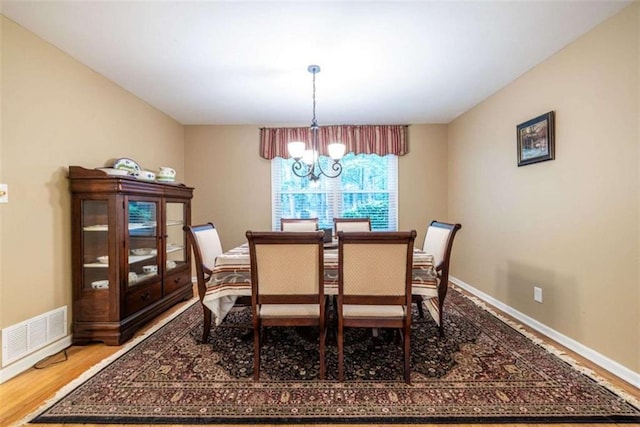 dining area with a chandelier, wood finished floors, and baseboards