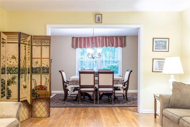 dining room featuring light wood-type flooring, baseboards, and a chandelier