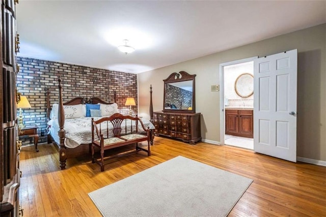 bedroom with light wood-type flooring, baseboards, and ensuite bath