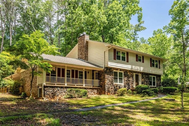 view of front of property featuring a chimney, a porch, stone siding, and a front lawn