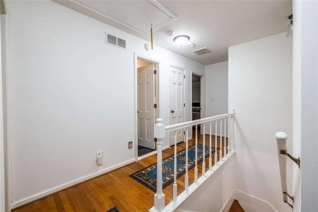 hallway featuring an upstairs landing, attic access, wood finished floors, and baseboards