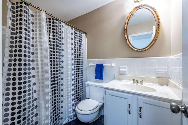 full bathroom with toilet, vanity, tile walls, a shower with shower curtain, and wainscoting
