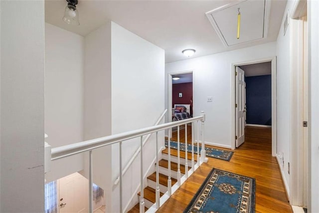 hallway with attic access, an upstairs landing, light wood-style floors, and baseboards