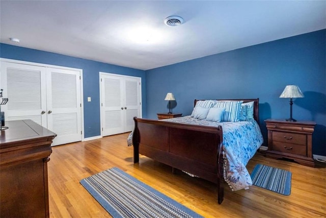 bedroom with two closets, wood finished floors, and baseboards