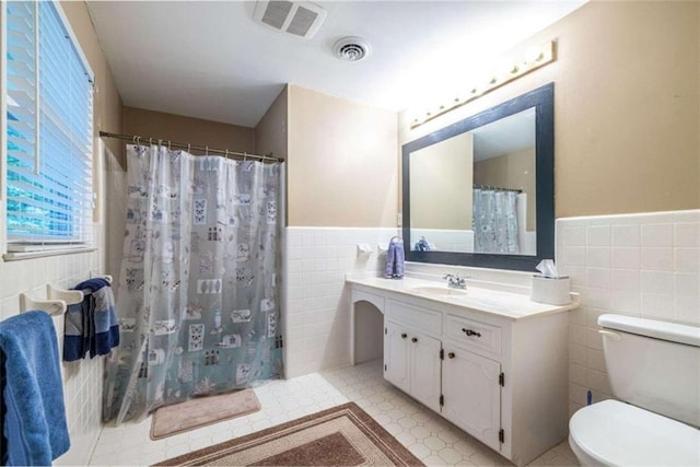 full bath featuring tile walls, toilet, wainscoting, vanity, and a shower with curtain