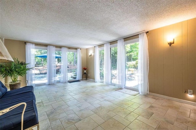 unfurnished living room with stone tile floors, baseboards, and a textured ceiling
