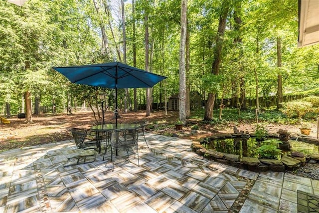 view of patio with outdoor dining space, an outbuilding, and a storage shed