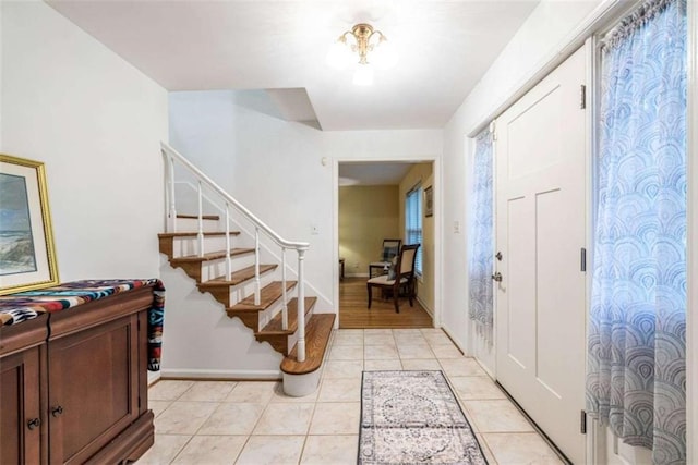 foyer entrance featuring stairway, baseboards, and light tile patterned flooring