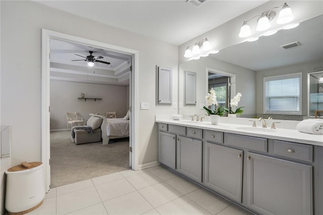 ensuite bathroom with double vanity, a raised ceiling, ensuite bath, tile patterned flooring, and a sink