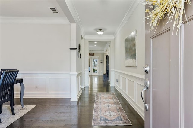 corridor featuring dark wood-style floors, a decorative wall, visible vents, and crown molding