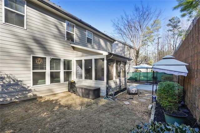 back of property with fence and a sunroom