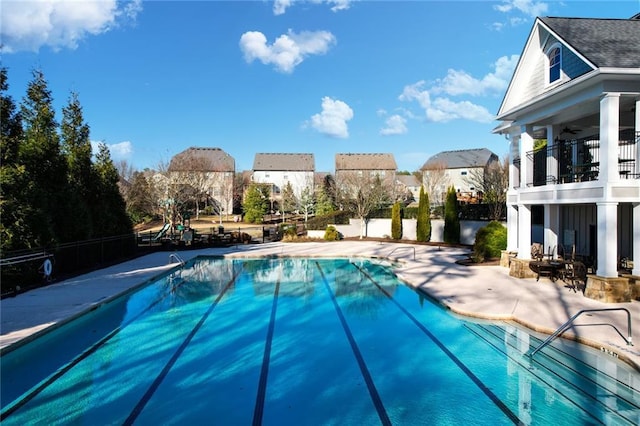 community pool featuring a patio area, ceiling fan, and fence