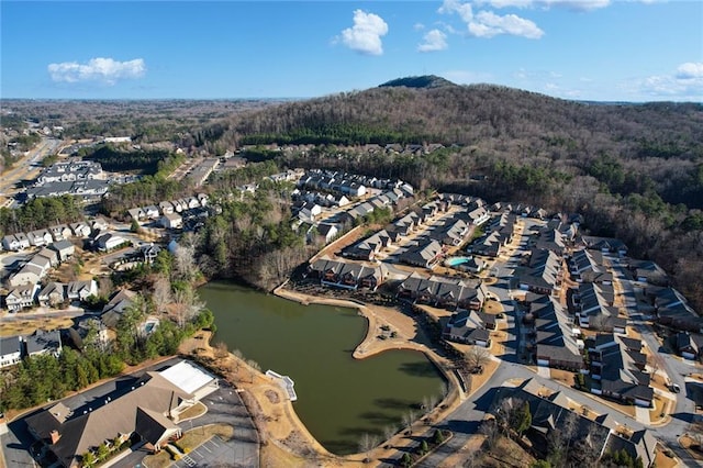 drone / aerial view featuring a water view, a wooded view, and a residential view