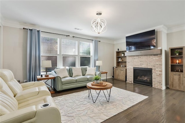 living room with ornamental molding, dark wood-style flooring, a fireplace, and an inviting chandelier