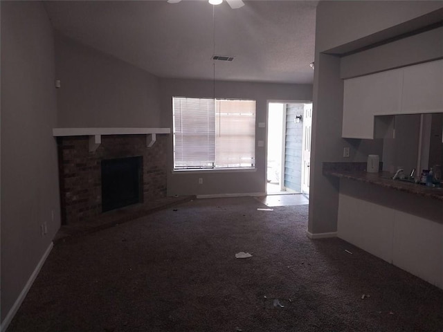 unfurnished living room featuring a brick fireplace, carpet flooring, visible vents, and baseboards