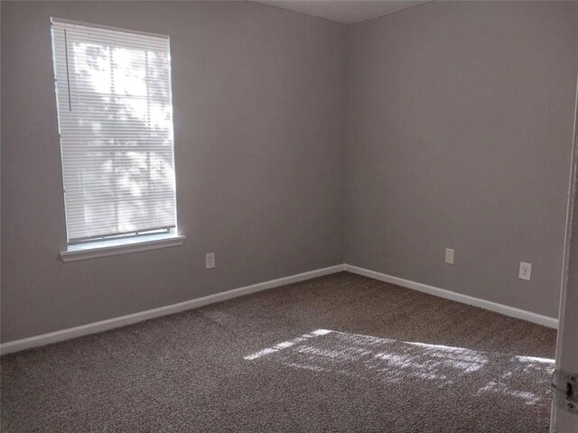 carpeted spare room featuring baseboards