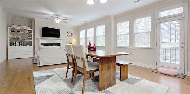 dining area with ceiling fan, light wood-type flooring, and crown molding