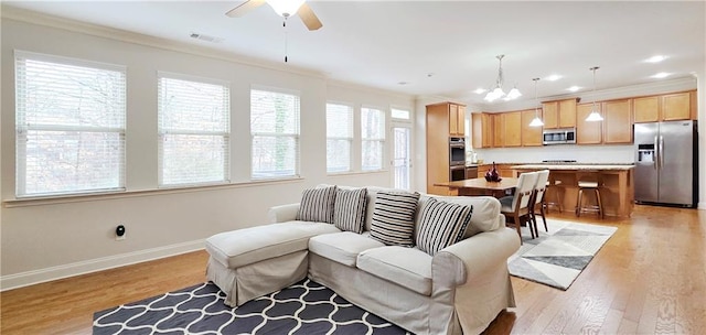 living room featuring light wood-type flooring, crown molding, and ceiling fan with notable chandelier