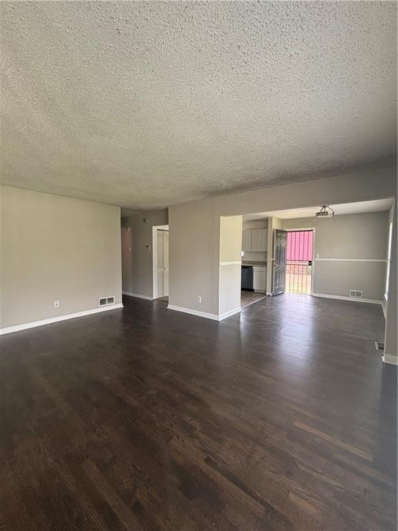 2830 Norgate Ln, Decatur, GA 30034 - unfurnished living room featuring dark wood-style flooring, a textured ceiling, baseboards, and visible vents
