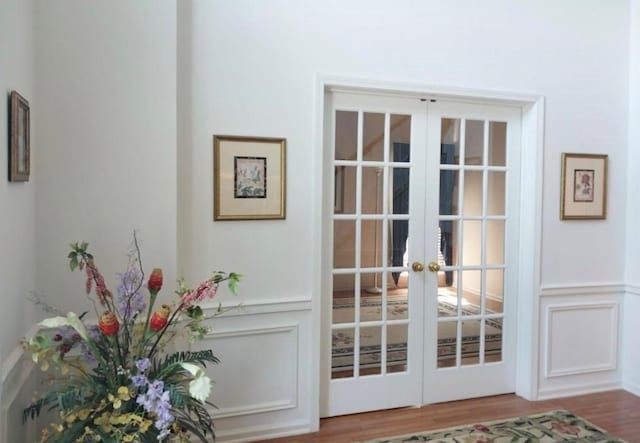 entryway featuring a wainscoted wall, french doors, wood finished floors, and a decorative wall