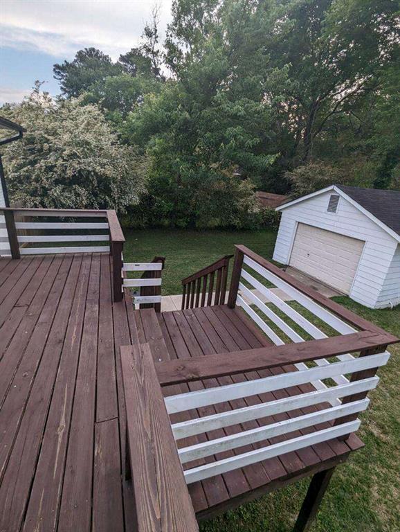 6977 Eunice Dr, Riverdale, GA 30274 - wooden terrace featuring a garage, a lawn, and an outdoor structure