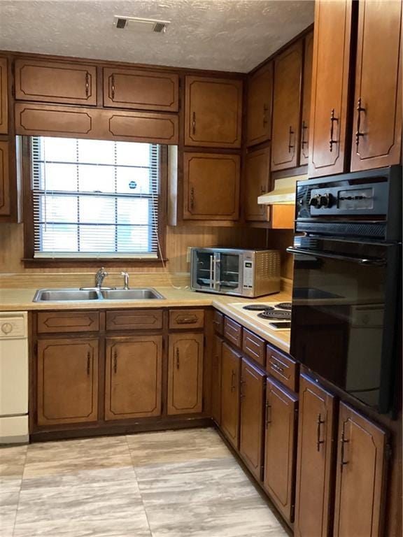 kitchen with light countertops, white appliances, a sink, and brown cabinets