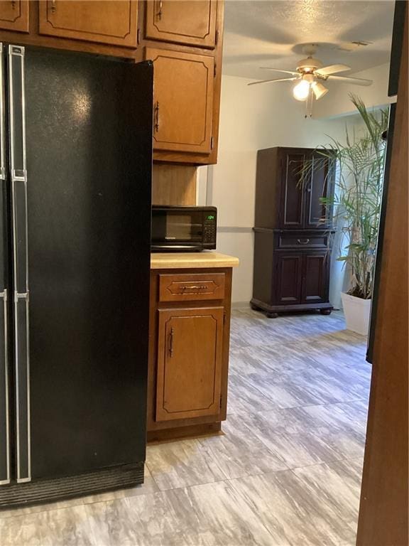 kitchen featuring ceiling fan, black appliances, light countertops, and brown cabinets