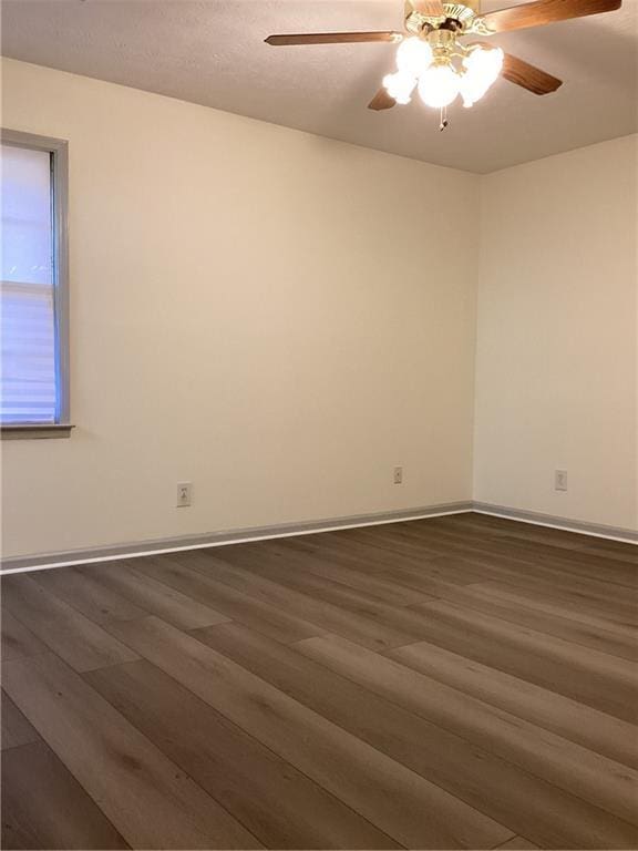 spare room with ceiling fan, baseboards, and dark wood-style flooring