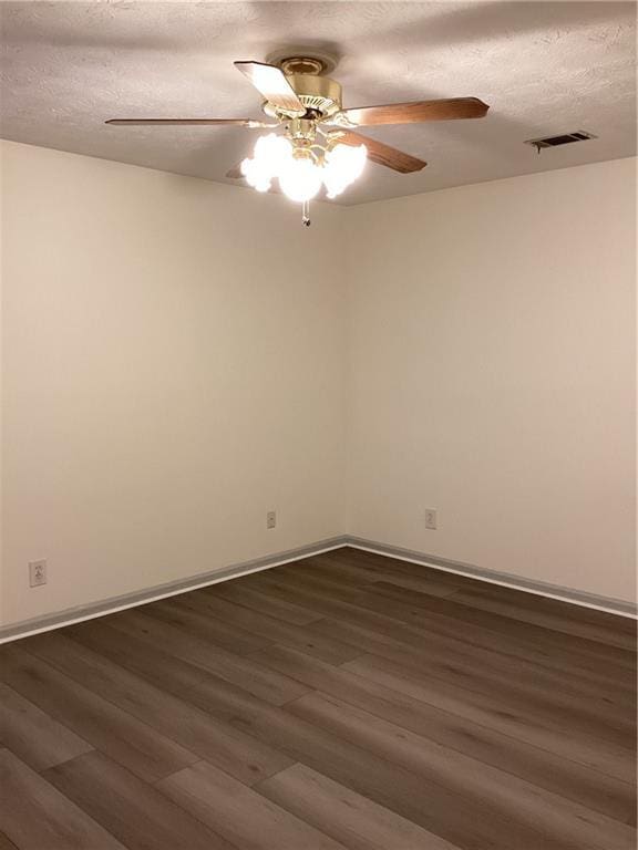 spare room featuring dark wood-type flooring, visible vents, and a textured ceiling