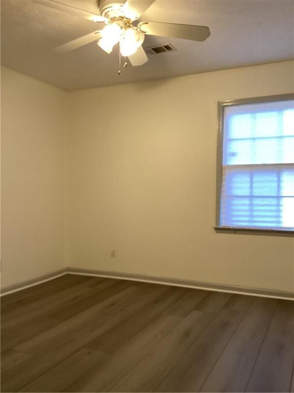 empty room featuring ceiling fan, baseboards, and dark wood-style flooring