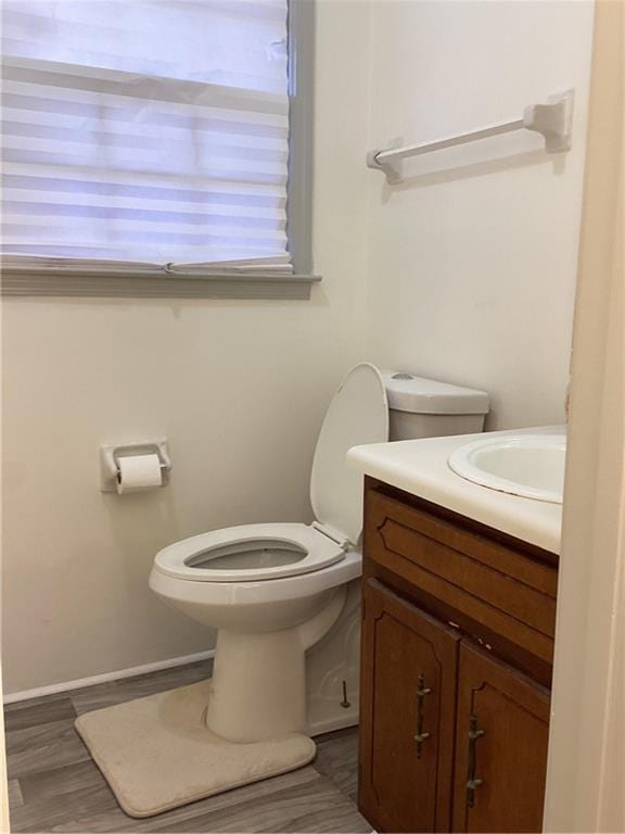 bathroom featuring baseboards, vanity, toilet, and wood finished floors