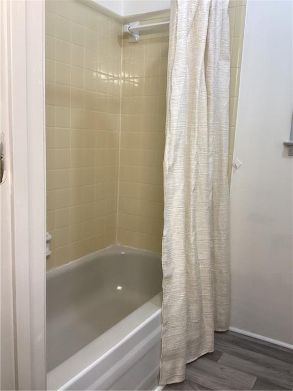 bathroom with shower / bath combo with shower curtain and wood finished floors