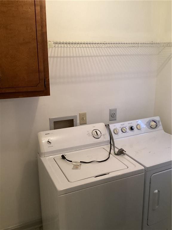 clothes washing area with washer and dryer and cabinet space