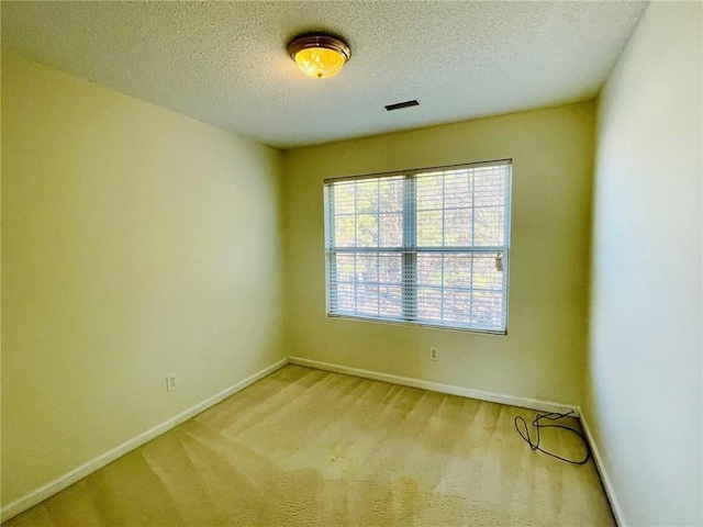 unfurnished room featuring carpet flooring, visible vents, a textured ceiling, and baseboards