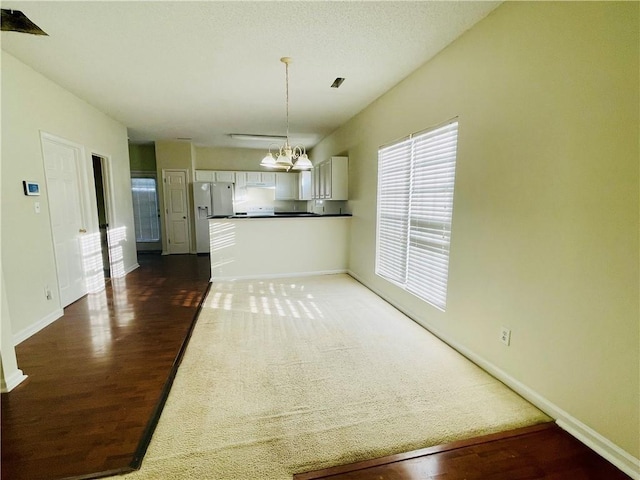 kitchen featuring white cabinetry, dark countertops, baseboards, and white fridge with ice dispenser