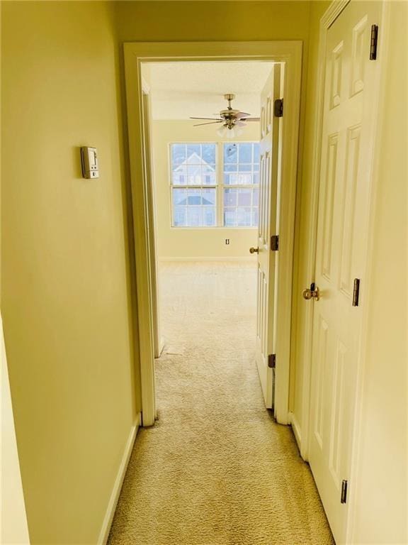 corridor featuring light carpet and baseboards