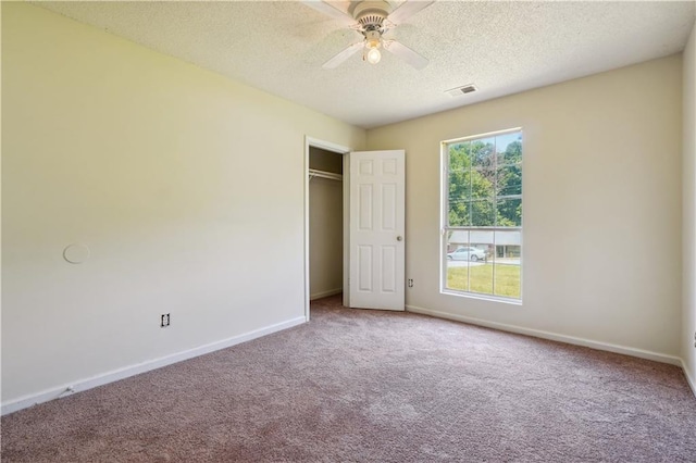 unfurnished bedroom with ceiling fan, a closet, a textured ceiling, and carpet