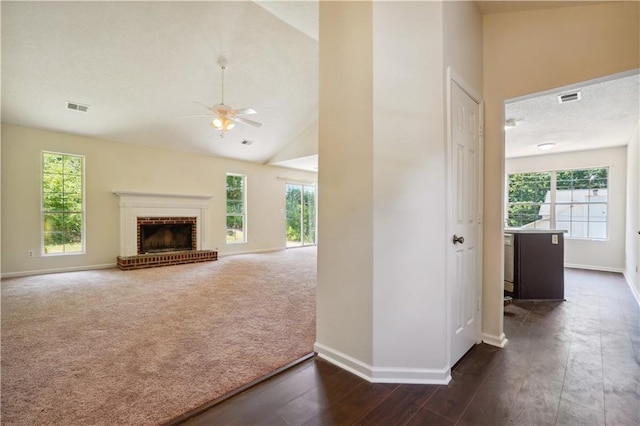 unfurnished living room with ceiling fan, a brick fireplace, high vaulted ceiling, and dark carpet